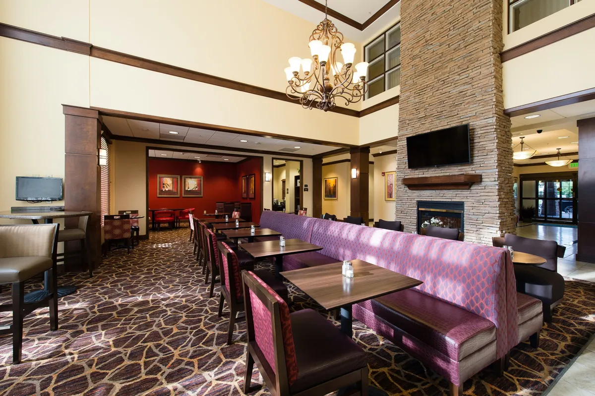 This interior image spotlights a communal lounge area featuring a chandelier, fireplace, comfortable seating arrangement, and decorative artwork. The space feels inviting and is well-suited for social gatherings or relaxing with friends after a day of exploration.