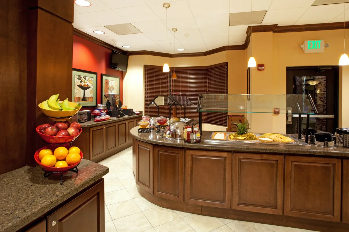 This image displays a bright breakfast bar with a colorful fruit selection and a fully stocked coffee station, inviting guests to start their day. The atmosphere is cheerful and inviting, encouraging both relaxation and social connection.